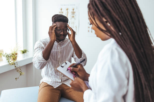 Patient en consultation neurologique se tenant la tête face à une neurologue